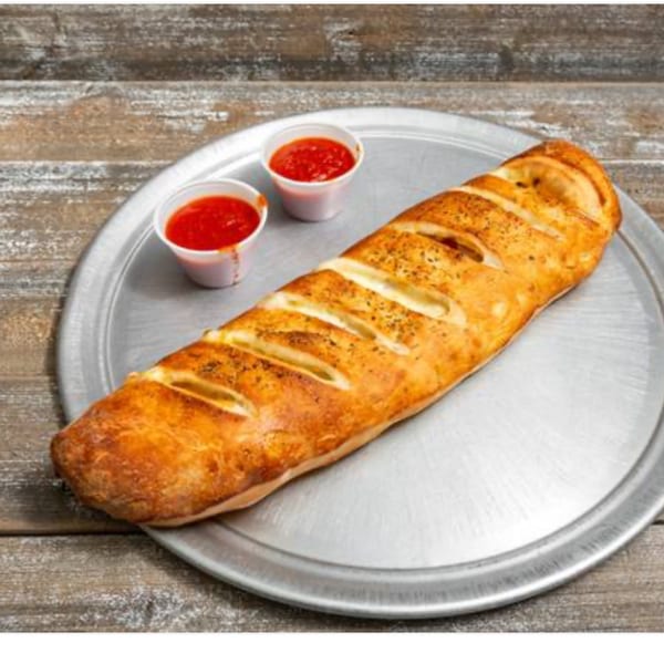 Shakey Jake's golden-brown calzone with cheese slits and two cups of marinara sauce on a metal tray.