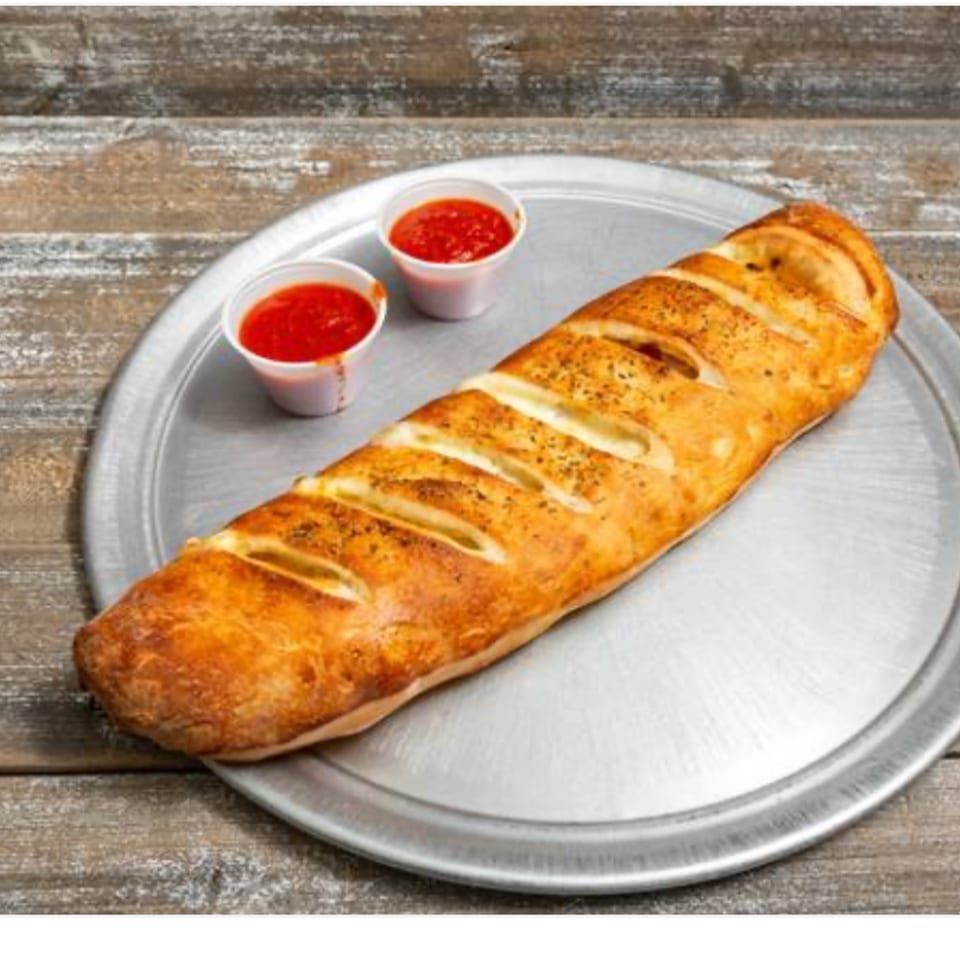 Shakey Jake's golden-brown calzone with cheese slits and two cups of marinara sauce on a metal tray.